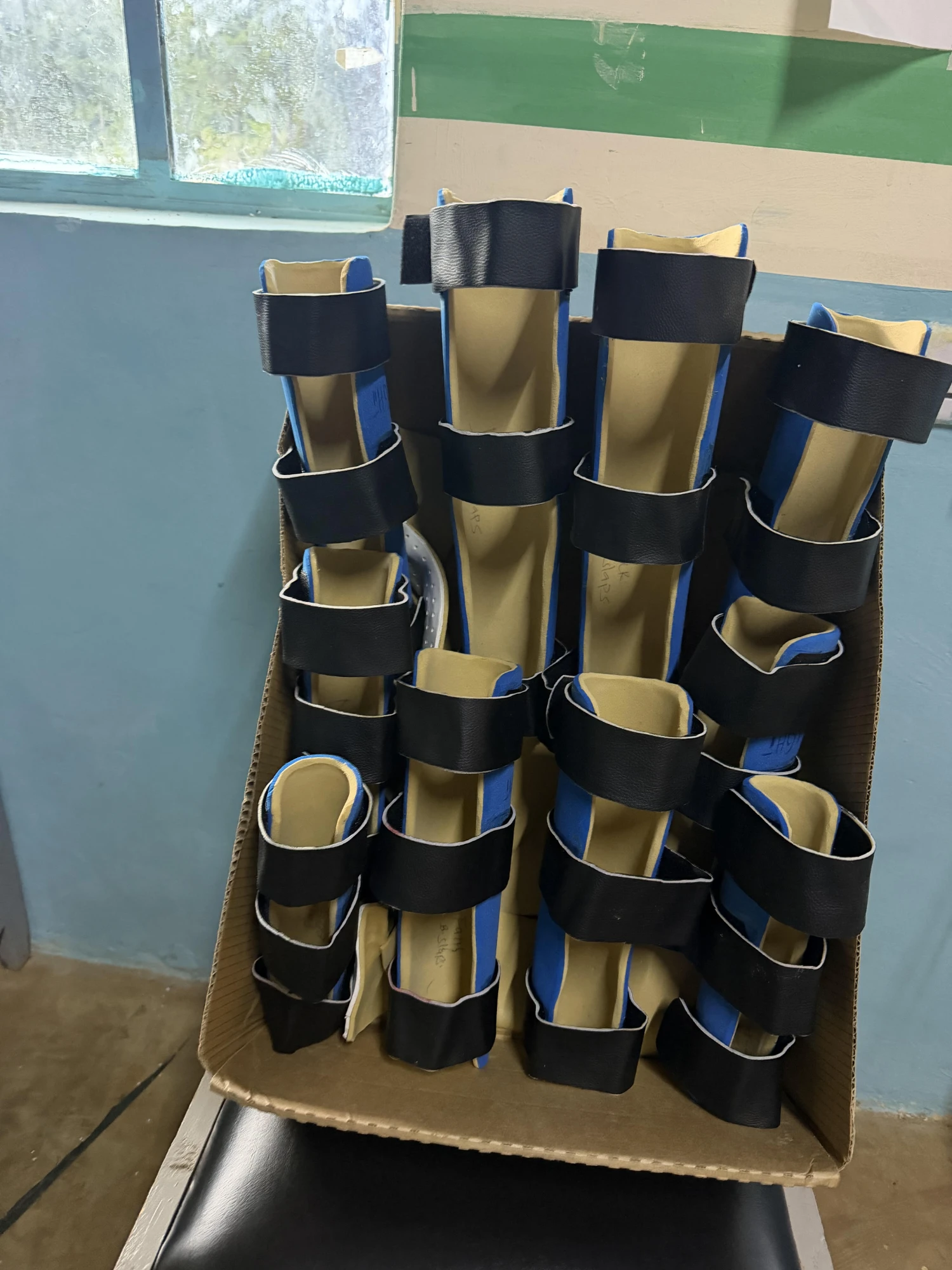 A box of finished elbow conformers and backslabs: foam-lined blue braces with black straps