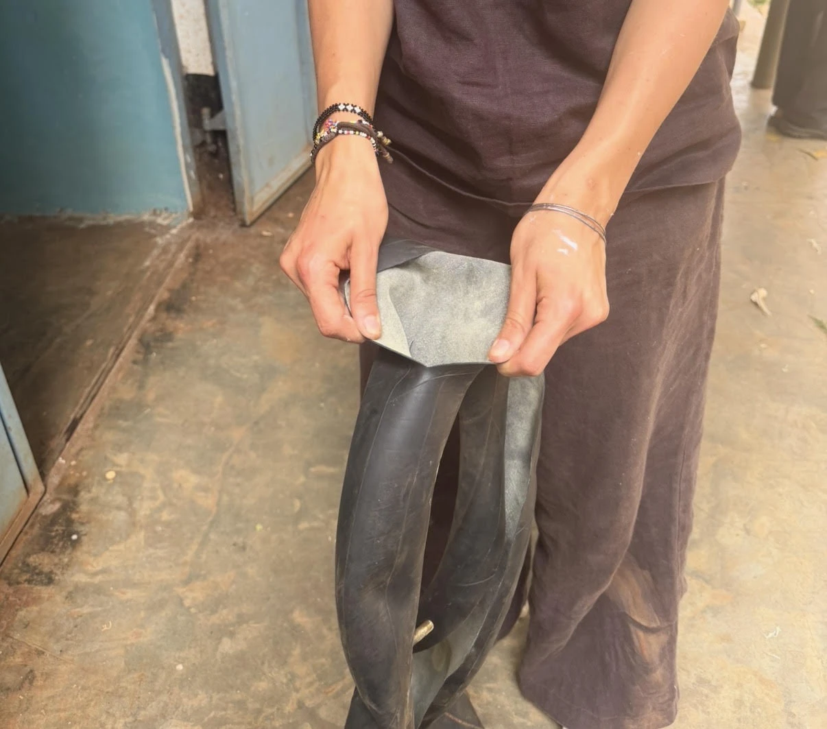 Leilani holding a length of black motorcycle inner tube with its inside surface peeled open, ready to cut into straps