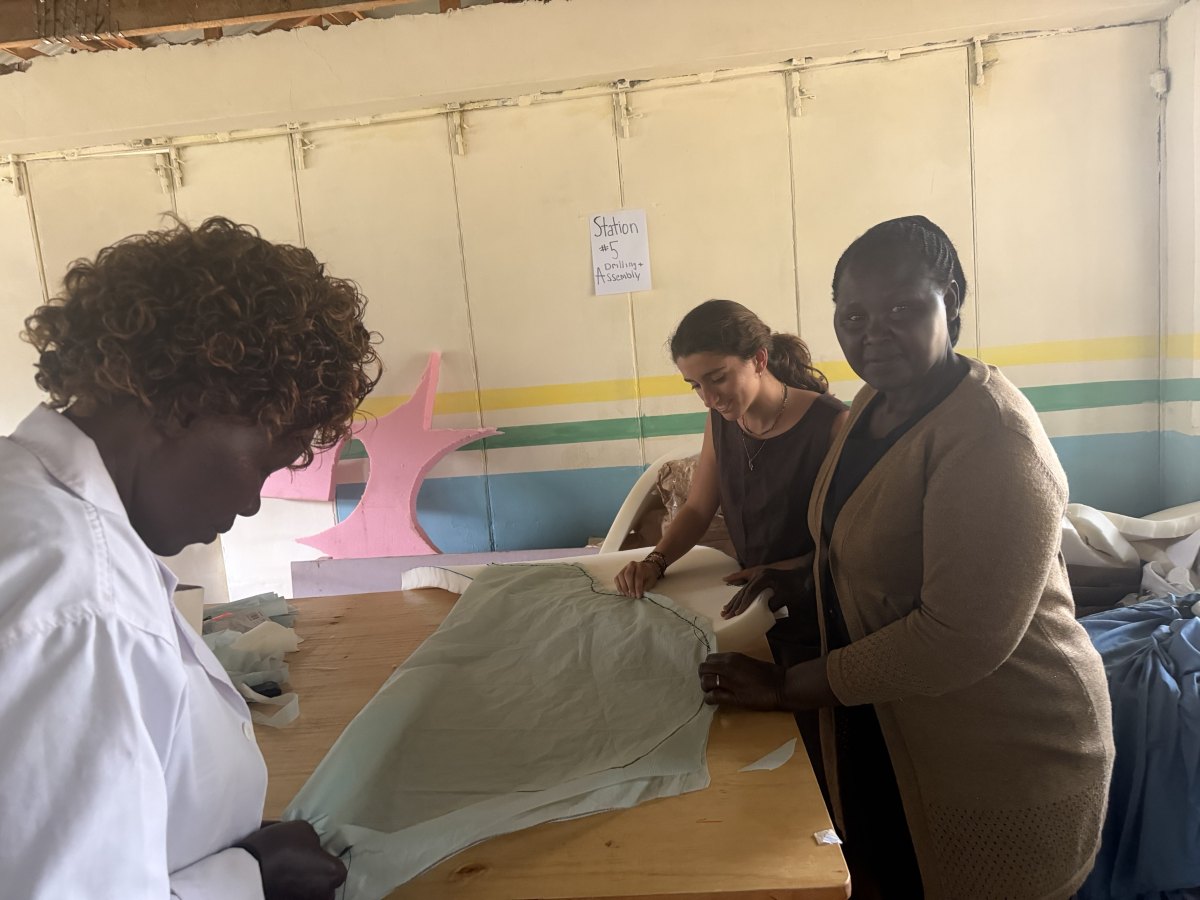 Leilani and two teachers at the workbench fitting a stitched pale green fabric cover over a shaped foam seat cushion