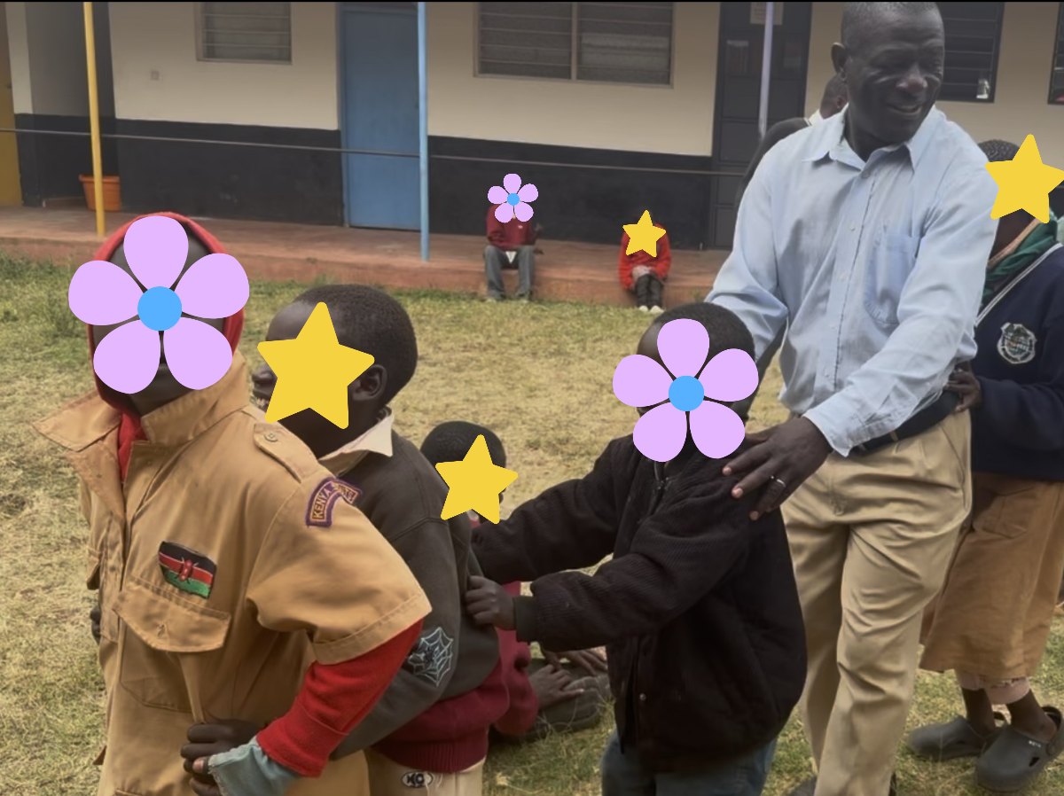 Learners dancing in a line on the grass with a teacher guiding them; their faces are covered with flowers and stars for privacy