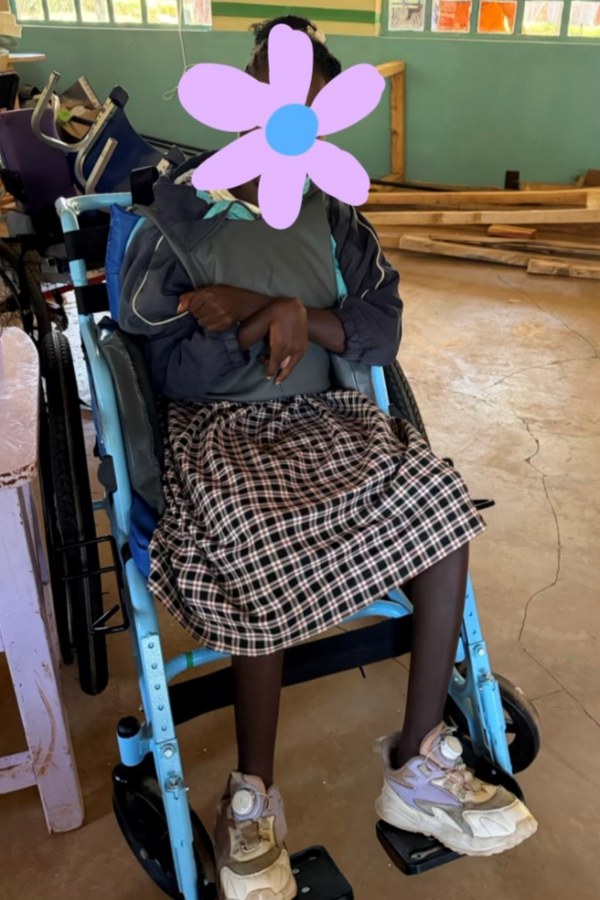 After fitting: the same learner sitting upright in a fitted wheelchair, supported by a padded chest harness, feet on the footrests; her face is covered for privacy