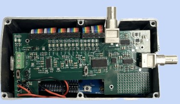 Close-up of the compact 2025 AC-DC EPG circuit board in its enclosure, with BNC connectors and ribbon cables